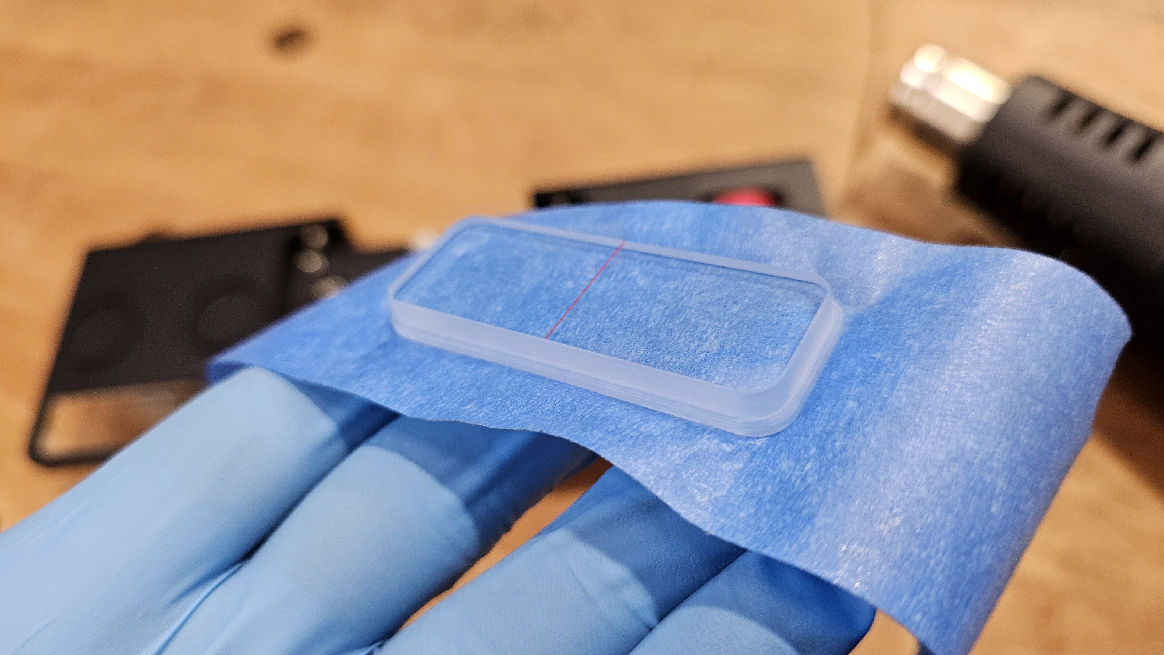 Step 4 — replacement viewer held on blue tape carrier, red hairline visible