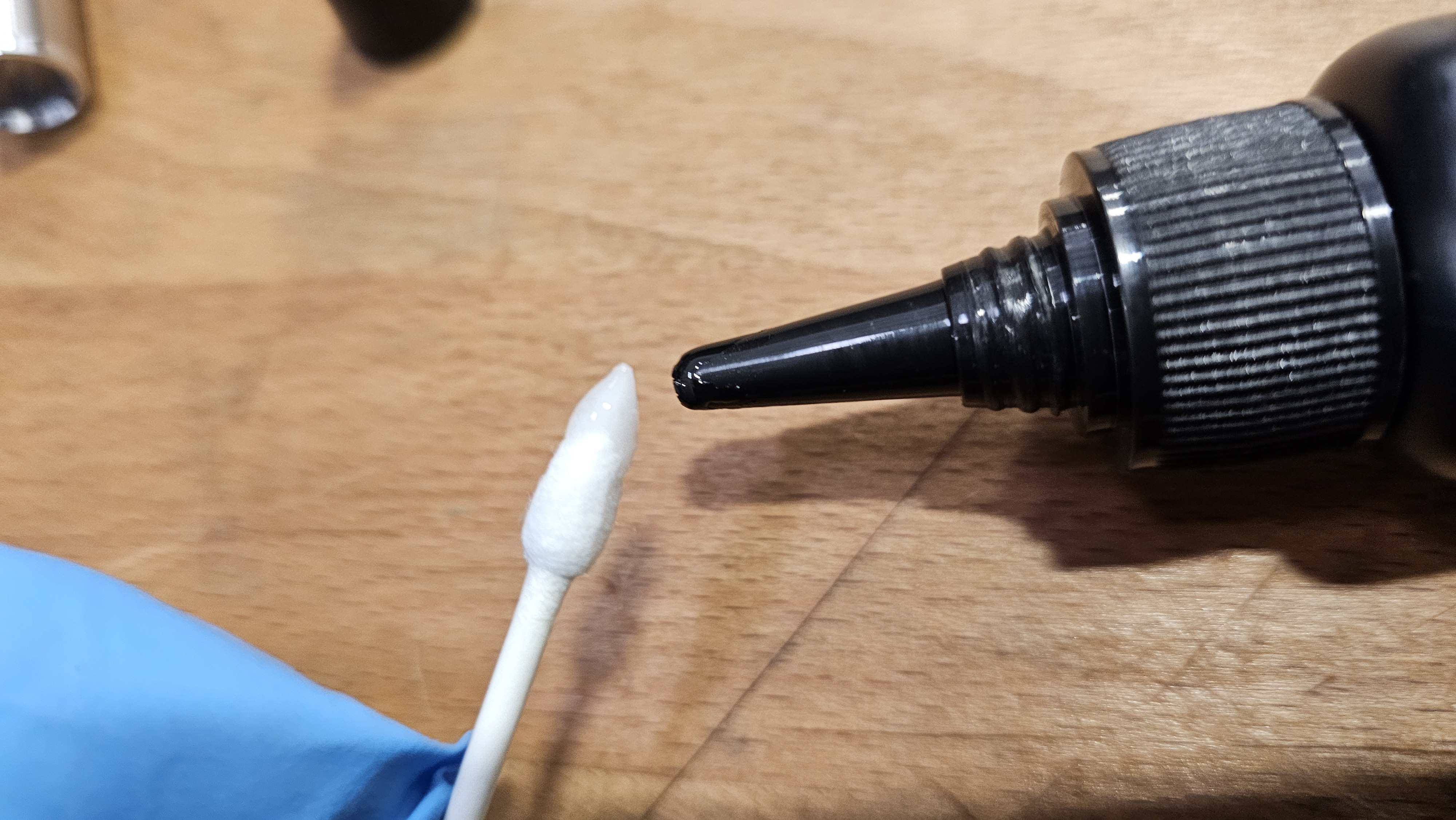 Step 6 — UV resin bottle dispensing a drop onto a cotton Q-tip swab