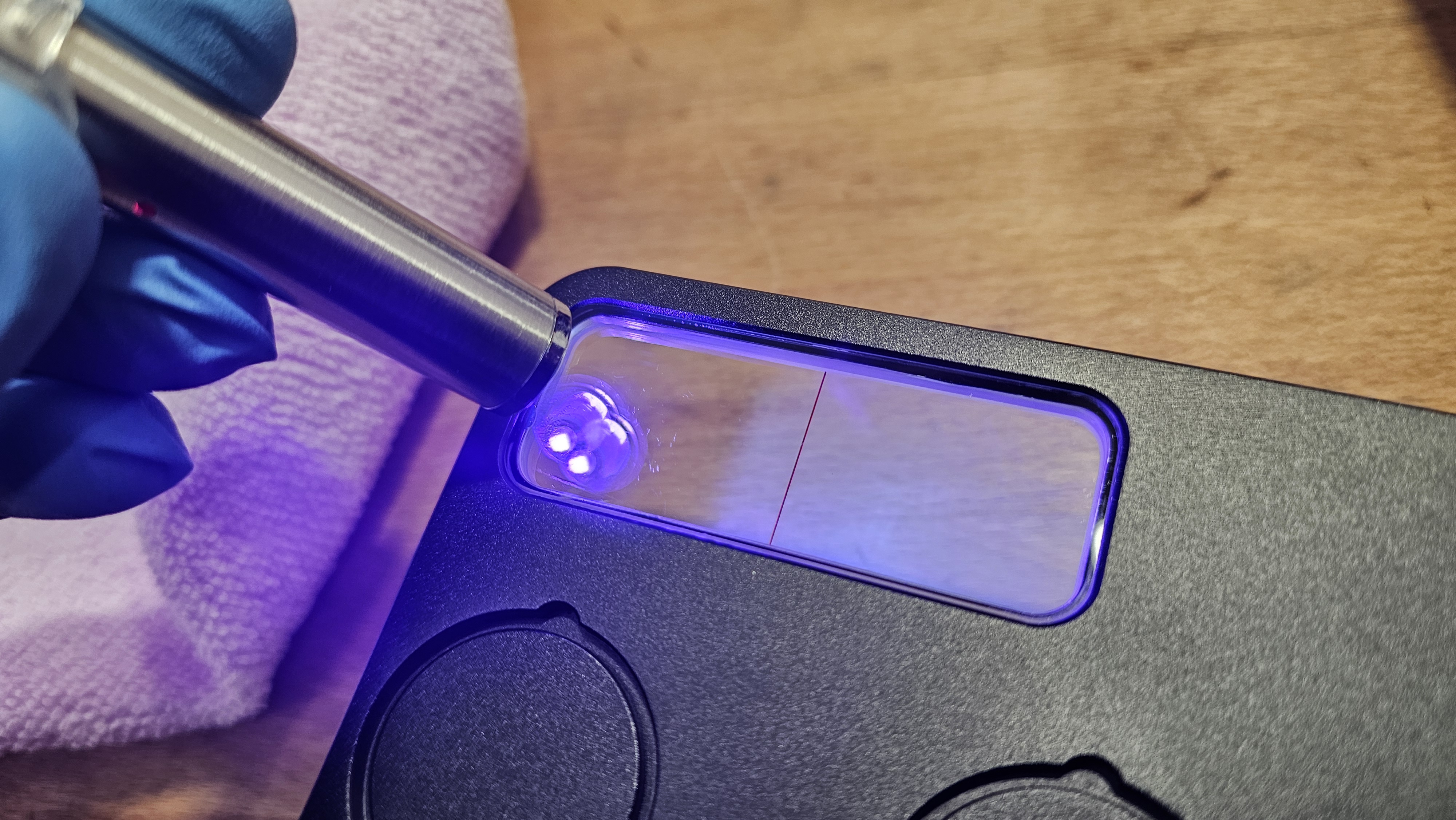 Step 9 — UV pen light curing resin seam around viewer, blue-purple UV light visible at edges