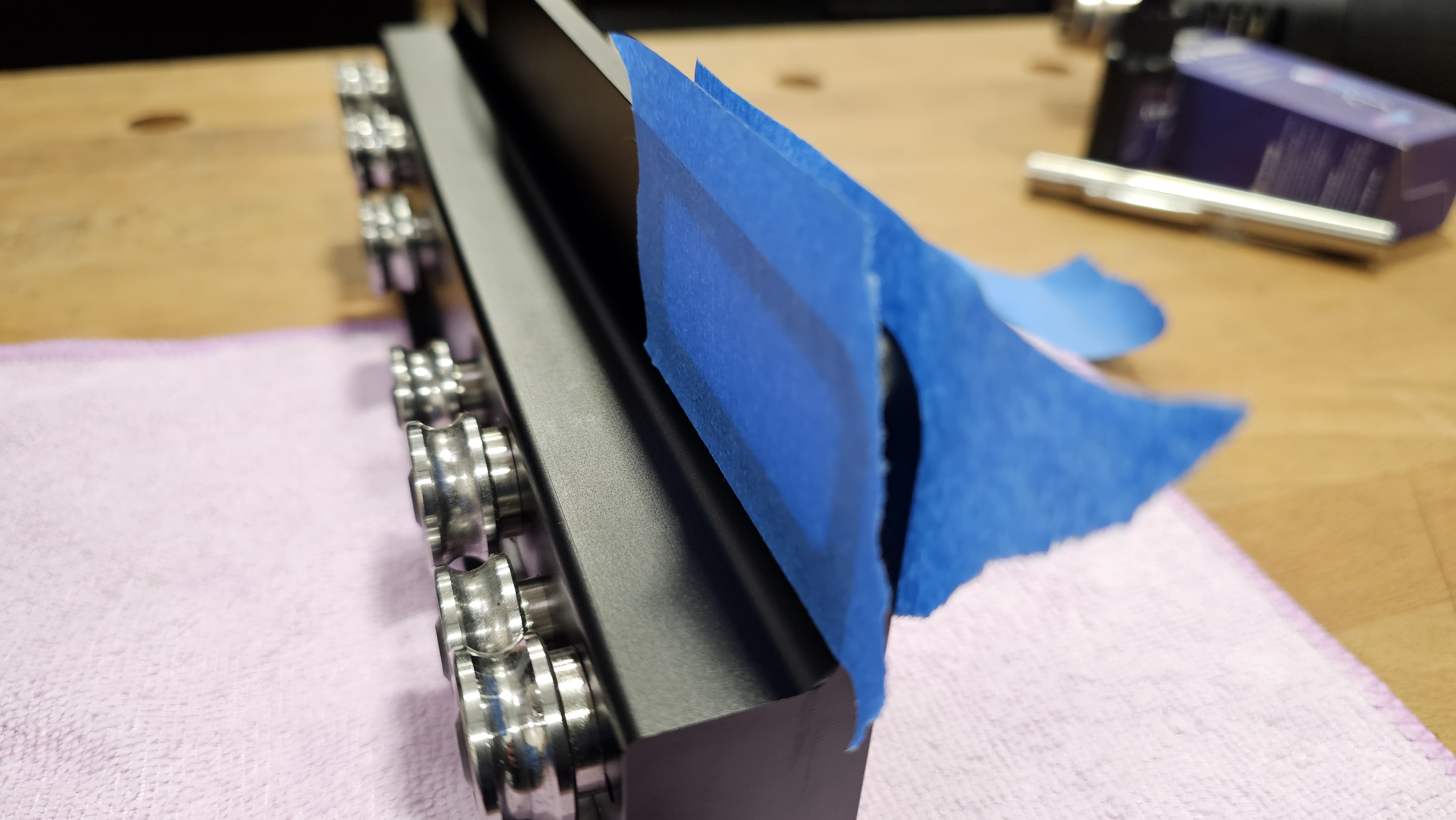Touch-up A — blue masking tape applied to the sides of the fence body across the viewer socket opening to contain resin