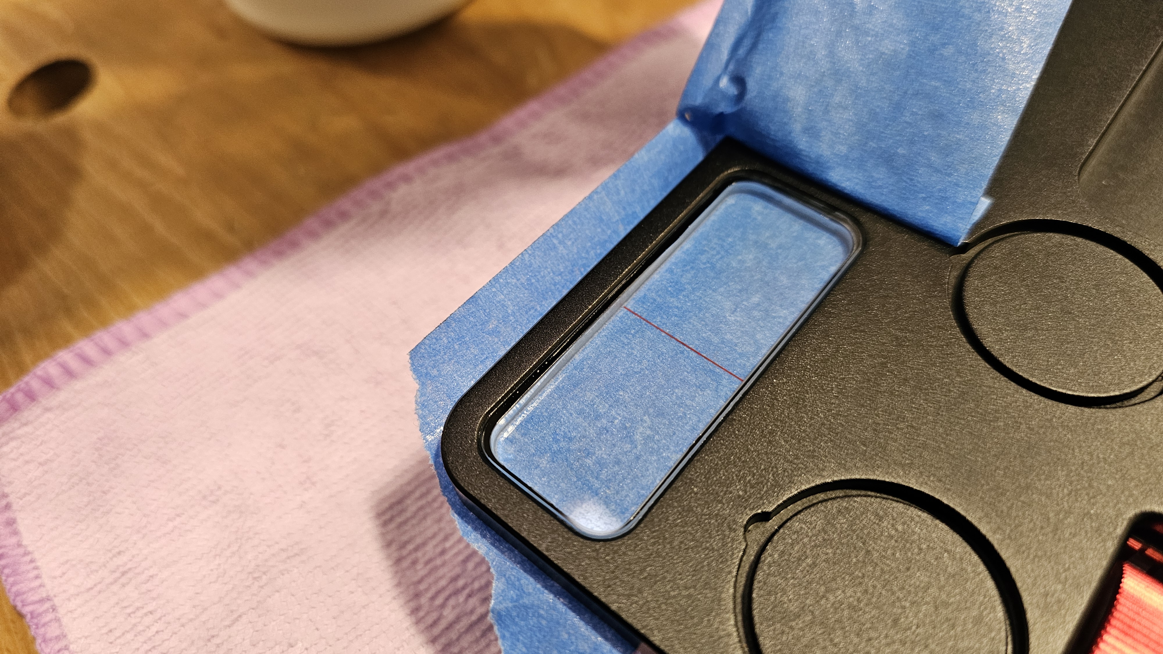 Touch-up B — top layer of blue tape being peeled back from viewer socket after filling from underside