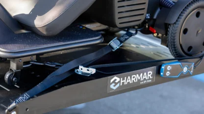 Close-up of a mobility scooter secured on a Harmar lift with straps and clamping mechanism.