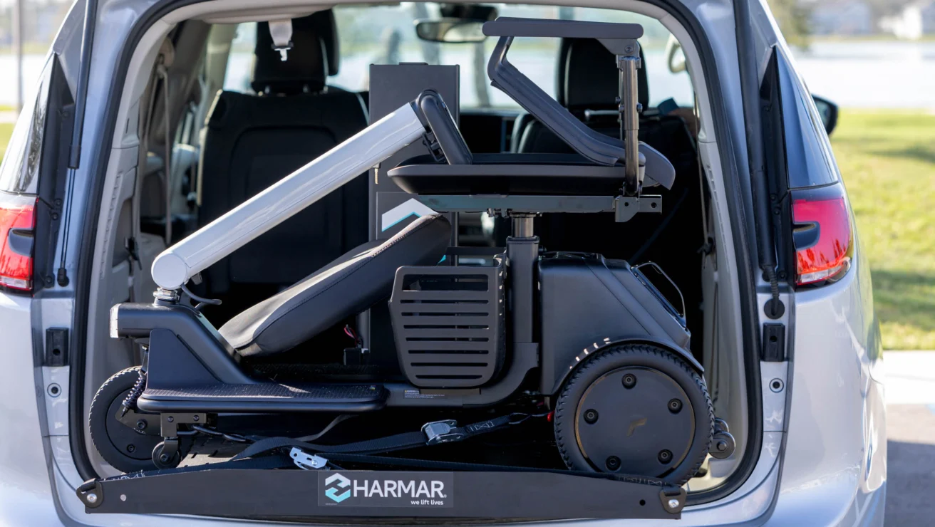A mobility scooter is securely mounted and stored in the back of a van using a Harmar lift system.