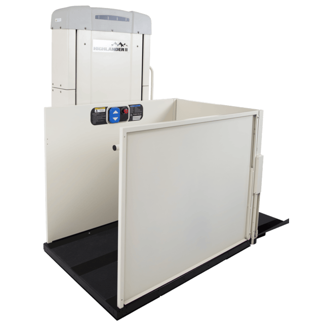 Vertical platform lift with safety gate, control panel, and handlebar, used for accessibility.