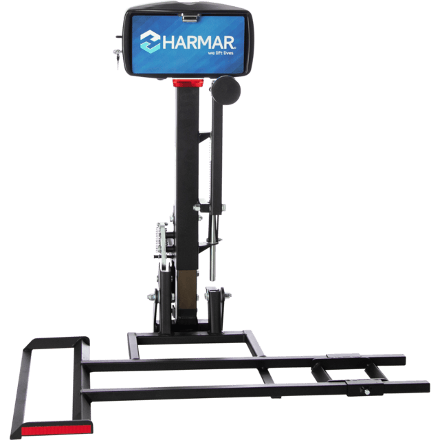 Vertical lift with a blue Harmar sign, featuring a platform and support structure for transporting mobility devices.