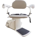 A beige stair lift chair with armrests, seatbelt, and footrest on a motorized base.
