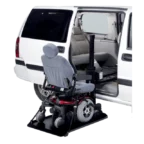 Wheelchair lift deploying from a white van, showing the interior seat aligned with the vehicle's open side door.