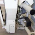 Close-up of a stairlift mechanism installed on a staircase, showing the motor, rails, and electrical components.