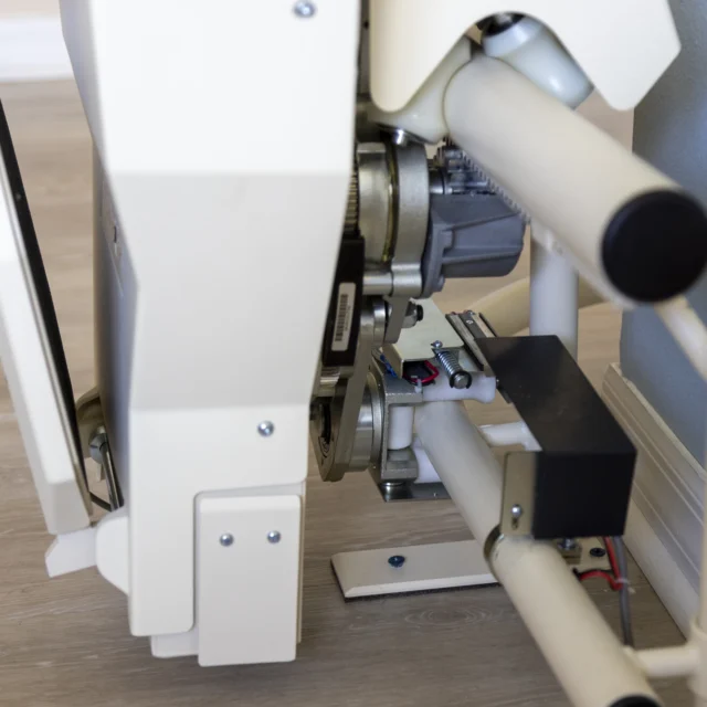 Close-up of a stairlift mechanism installed on a staircase, showing the motor, rails, and electrical components.