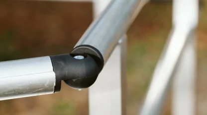 Close-up of a metal railing with a black elbow connector, against a blurred background.