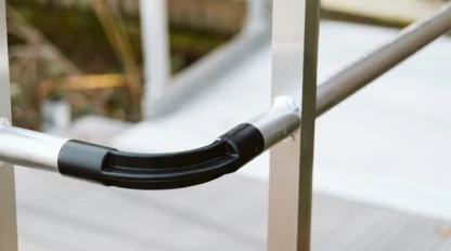Close-up of a metal railing with a curved black hand grip, positioned on a ramp or walkway.