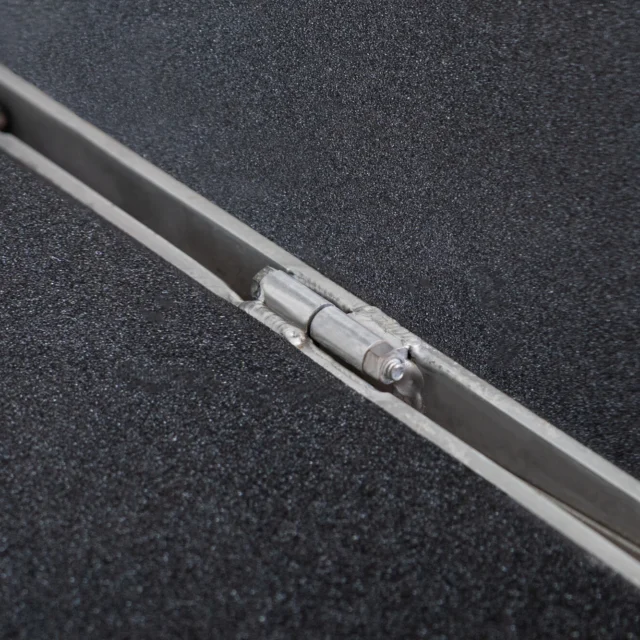 Close-up of a metal hinge embedded in a textured, dark surface, possibly part of a folding mechanism.