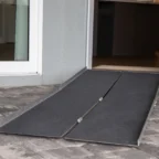 A portable wheelchair ramp leads into a building from a paved outdoor area.