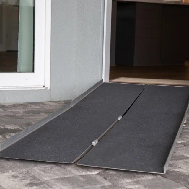 A portable wheelchair ramp leads into a building from a paved outdoor area.