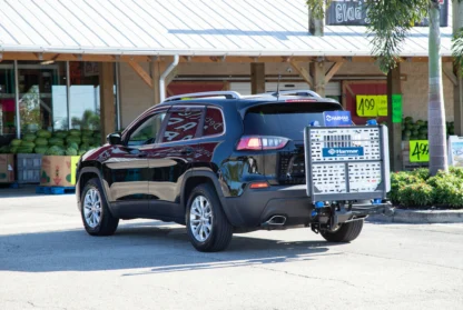 An SUV in a parking lot with a lift attached to the back, displaying the "Harmar" brand.
