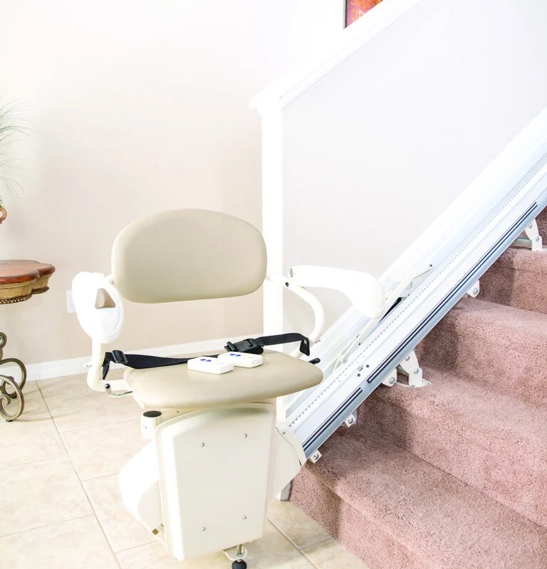 Stair lift on a carpeted staircase next to a small table with a potted plant in a bright room.