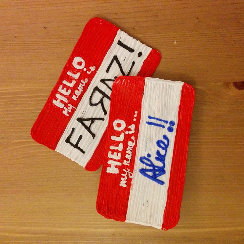 Two red and white nametags on a wooden table, showcasing 3D pen art.