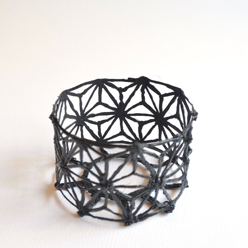 Close-up of black wire bracelet on white surface – 3D pen art.