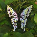 Vibrant 3D pen art: colorful butterfly on green leaves in a garden.