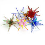 Colorful 3D pen art: Christmas stars arranged on white surface.