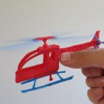 3D pen art of a hand holding and pointing at a toy helicopter.
