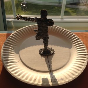 Man using 3D pen creates statue of giraffe on paper plate with knife