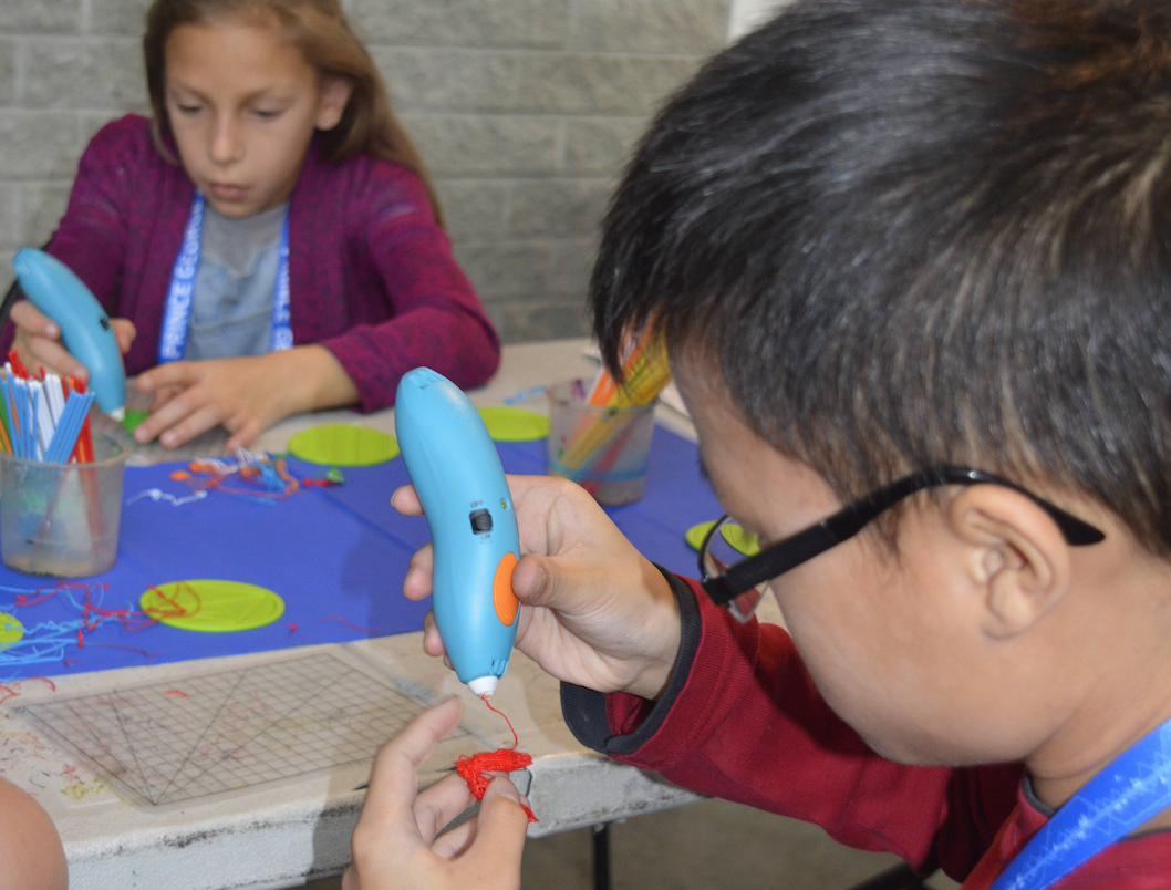 Children creating blue and orange 3D pen art at Bc Makerlab.