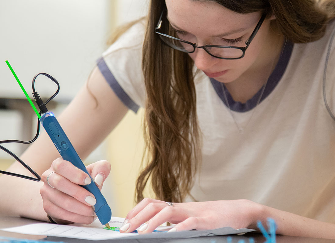 Creative woman uses 3D pen to draw glasses on paper