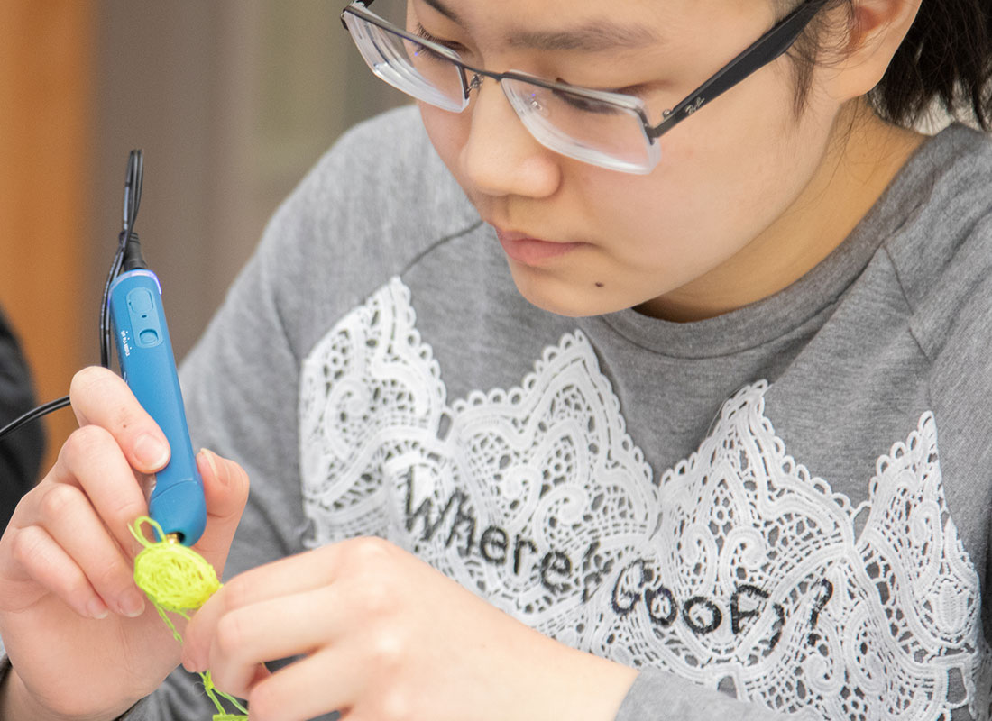 Young girl creating cell phone 3D pen art.