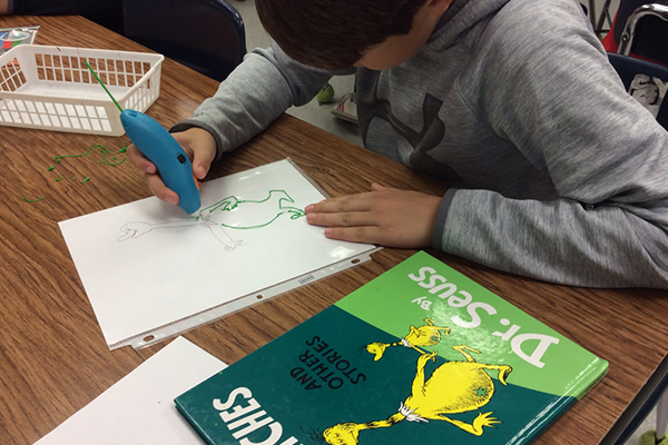 Boy creating 3D pen art at a table