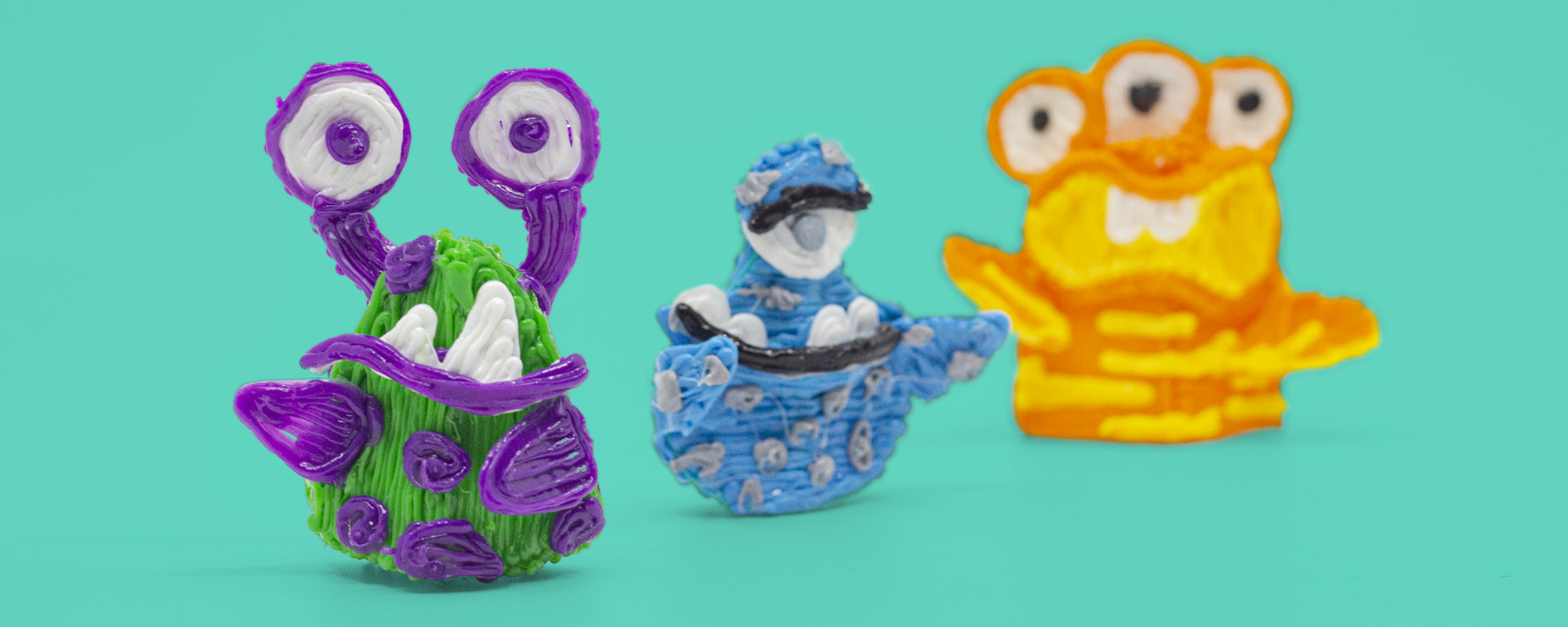 3D pen art: Monsters on green surface, colorful plastic toys.