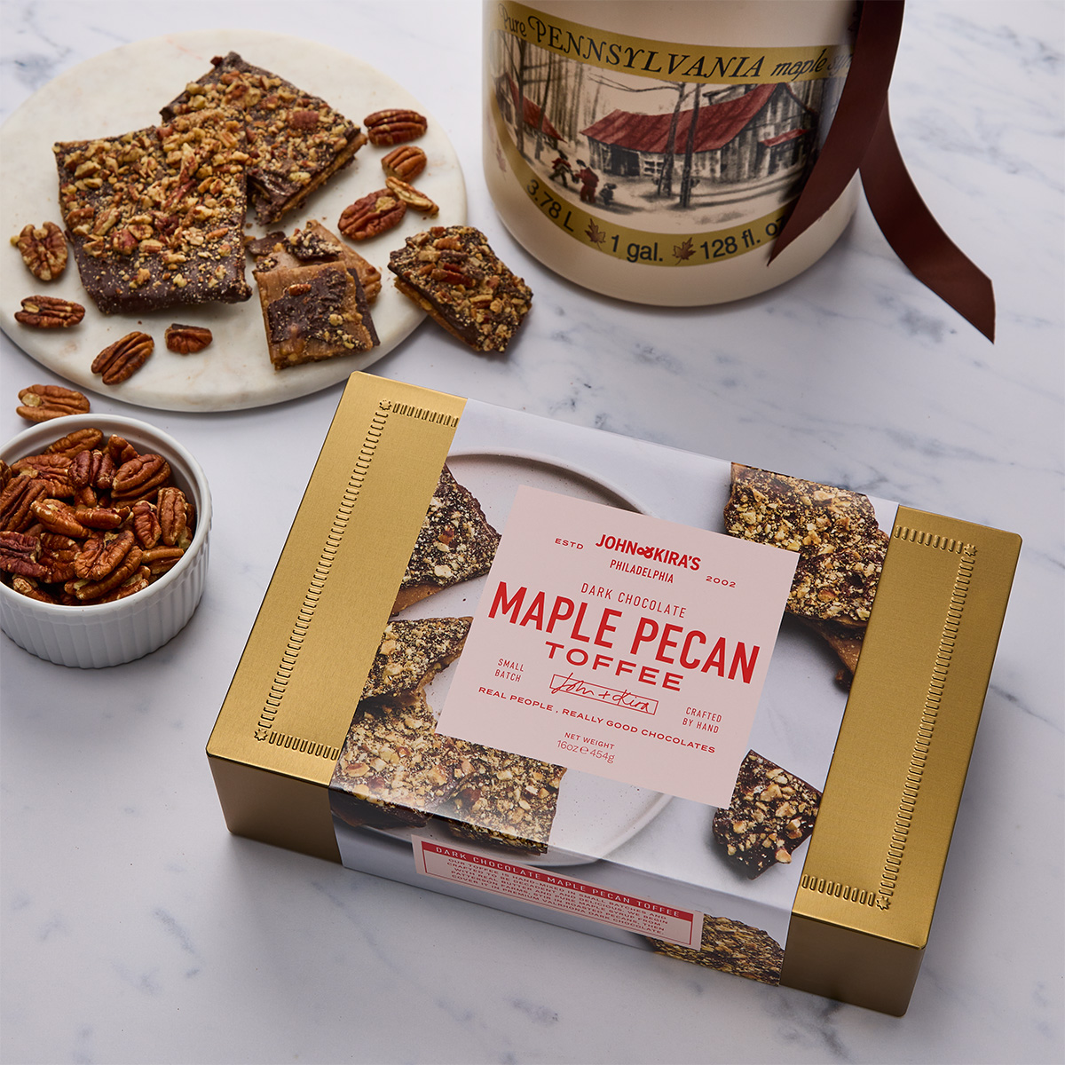 A reusable tin gift tin filled with dark chocolate maple pecan toffee next to the ingredients