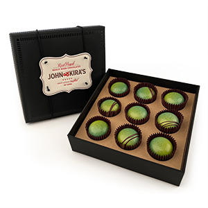 An open box of bright green chocolate bon bons that shows the black exterior of the package as well as the letterpress tag.