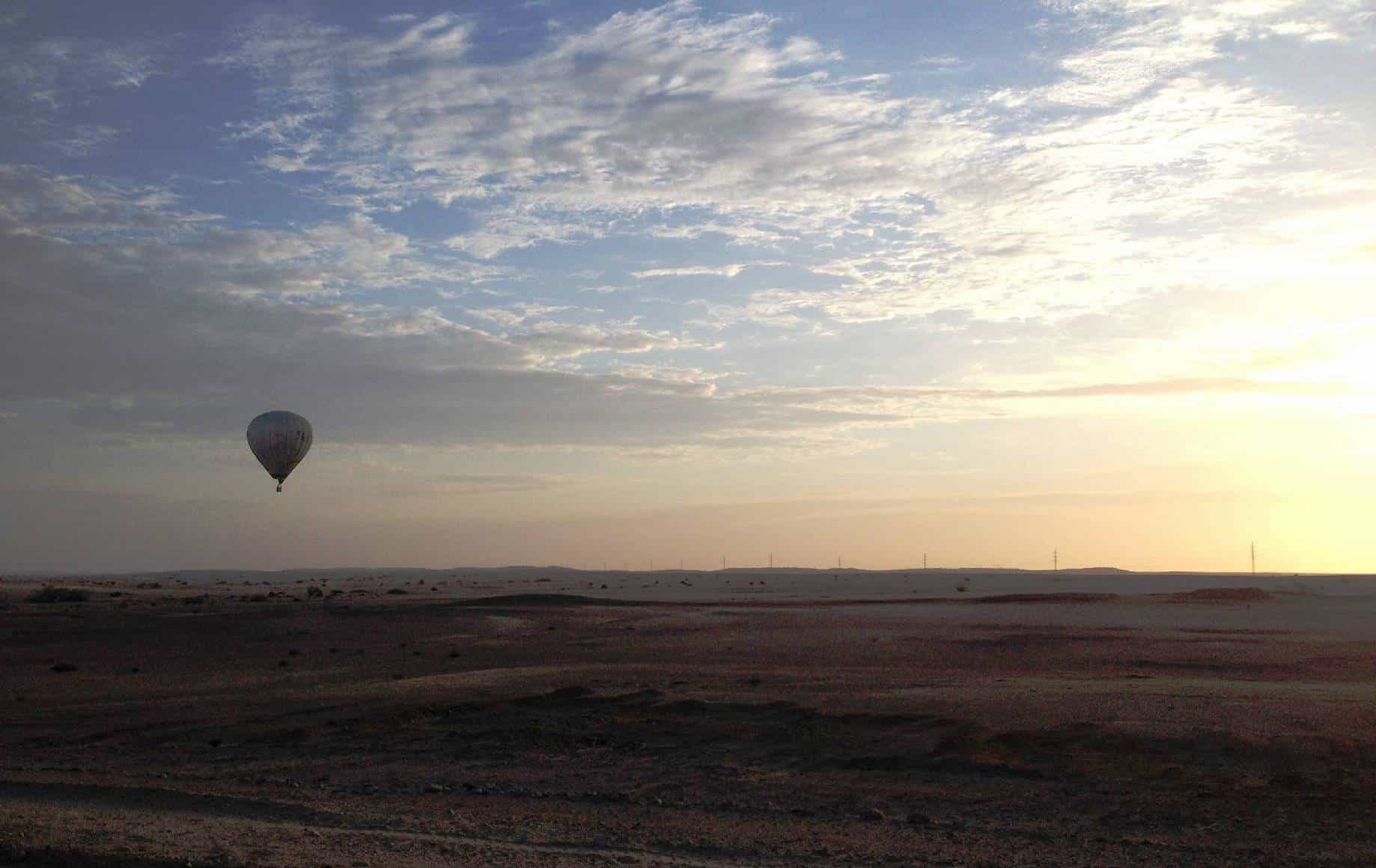 A sunset in the sky with a hot air balloon in the distance
