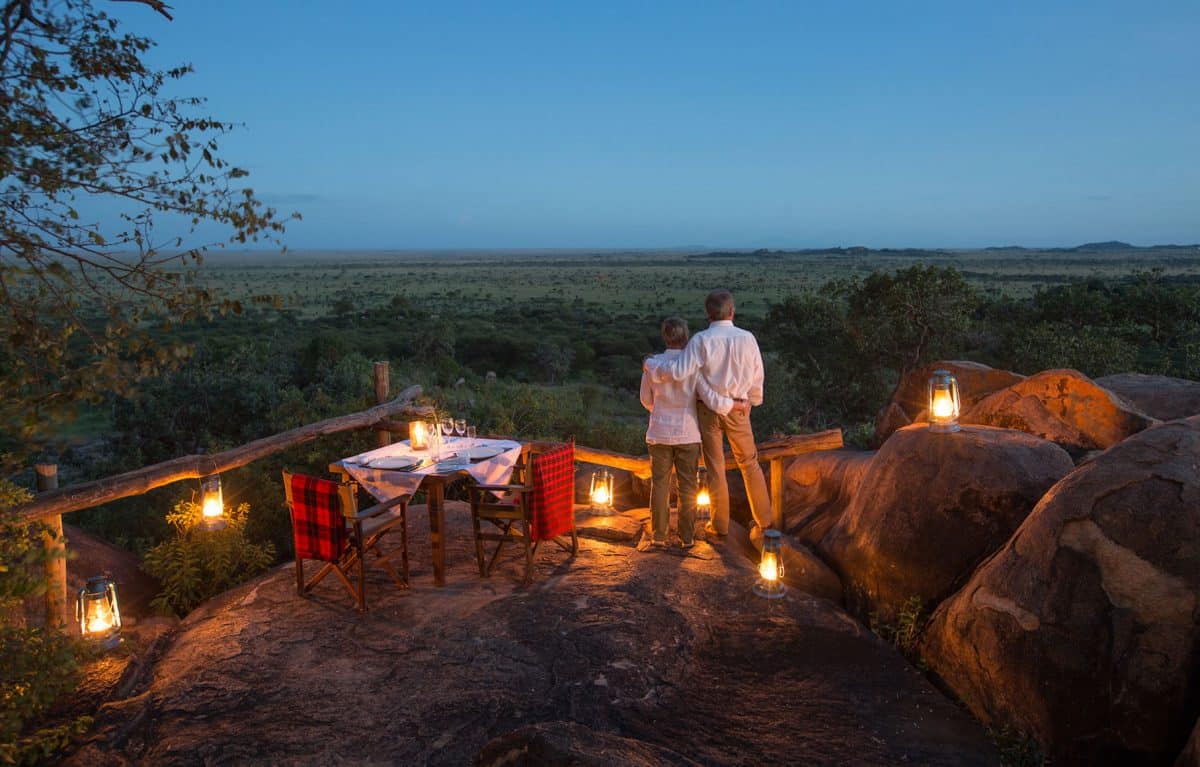 A couple looking out at the view off their patio at night.