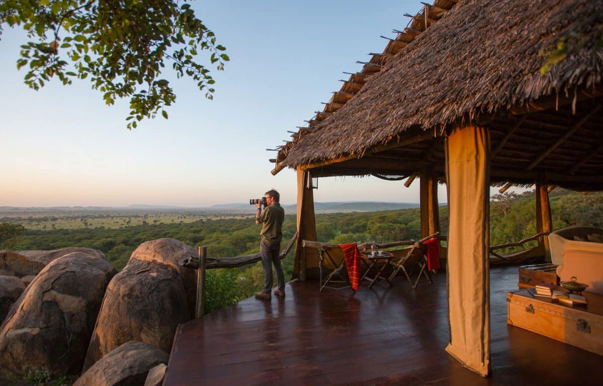 A man taking a picture on the deck of the Serengeti Pioneer Camp.