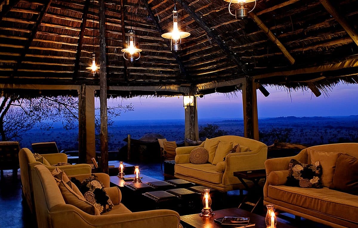 A group of chairs and tables with the sun setting in the distance.