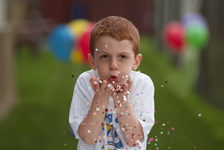 A camper blowing confetti from his hands.