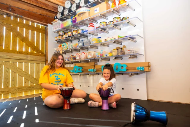 A CIT and camper playing drums.