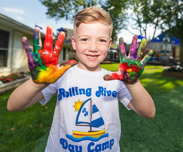 A young camper with paint on his hands.