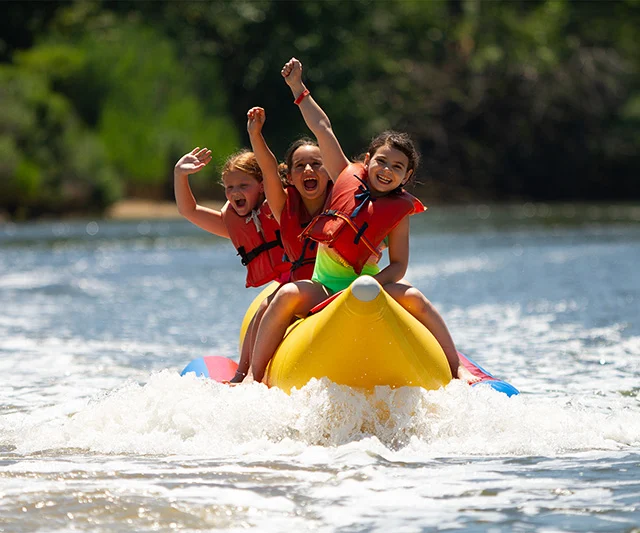 Three campers riding a banana boat.