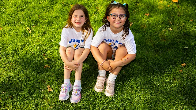 Two campers sitting on the grass, smiling.