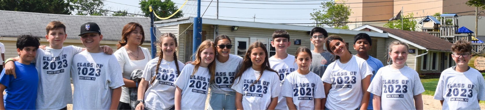 A group of students wearing "Class of 2023" shirts stand together outdoors, smiling at the camera.