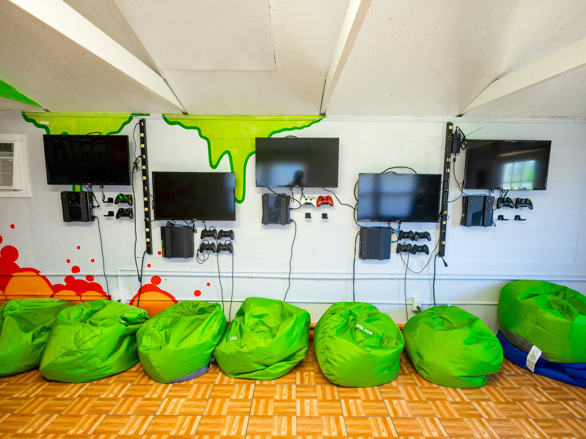 Bean bag chairs lined up against a wall and TVs mounted on the same wall.