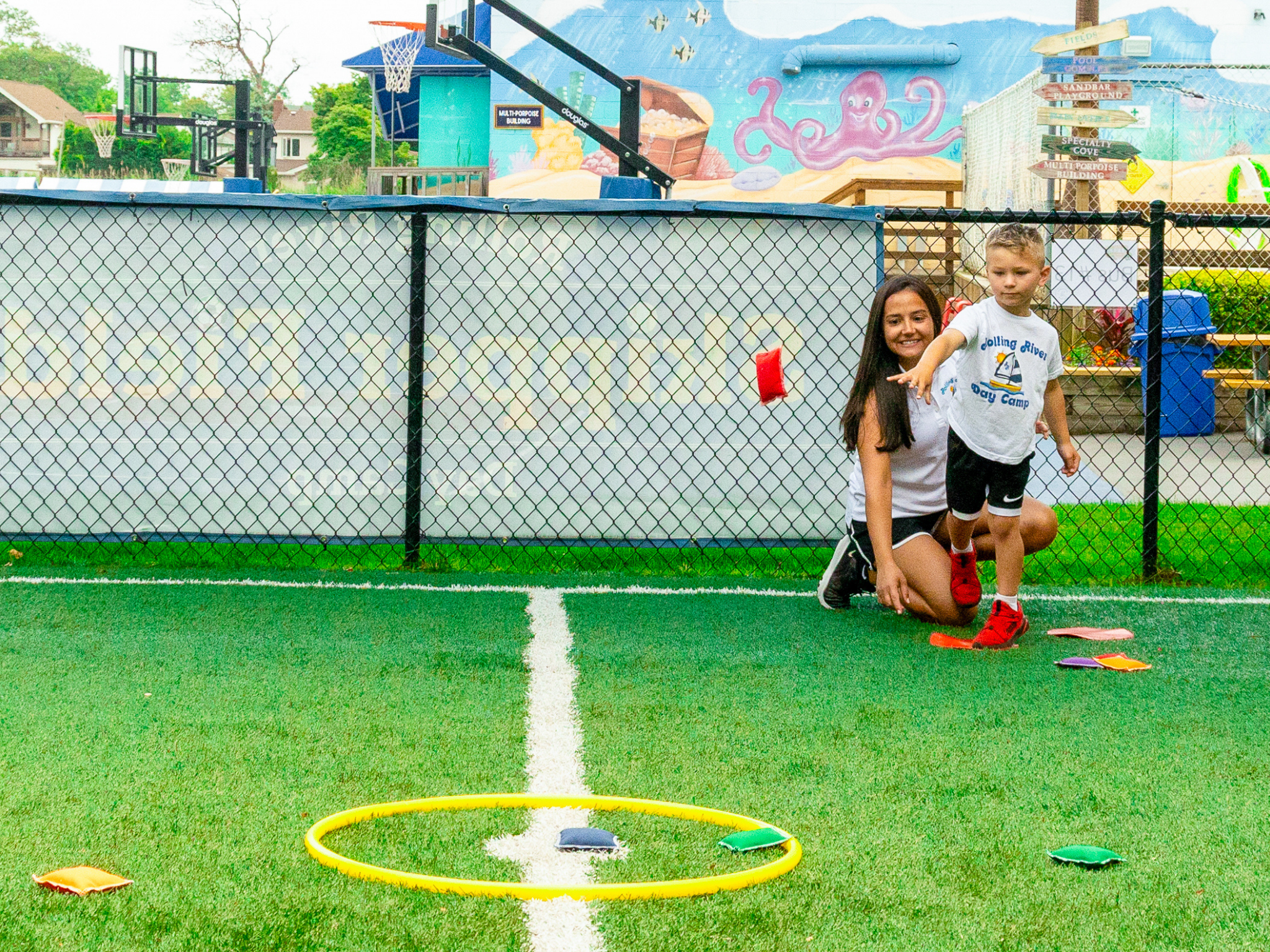 A young camper throwing a bean bag.