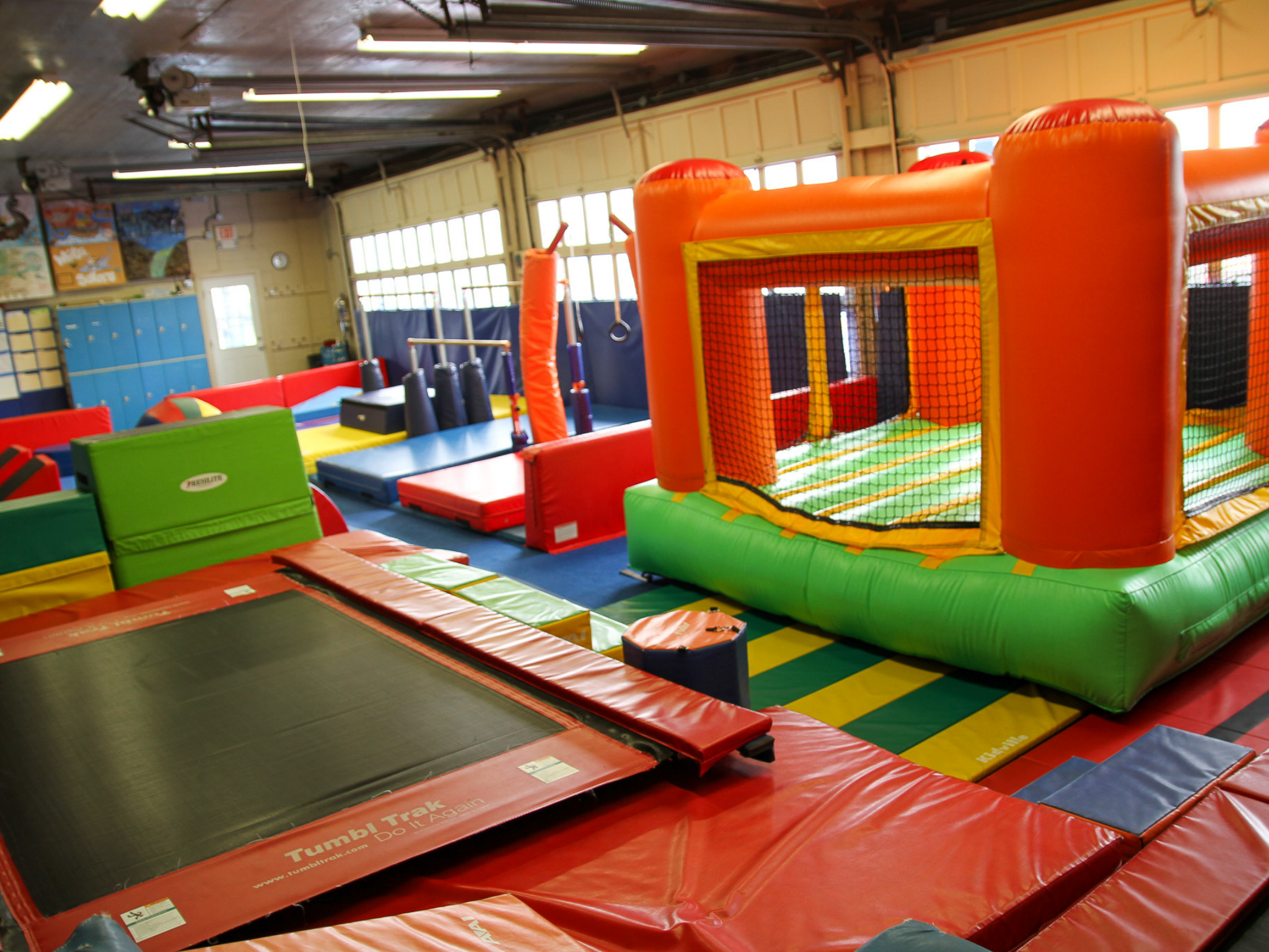 indoor tumbling center featuring trampolines, bounce house, gymnastics bars, balance beam and ninja course.