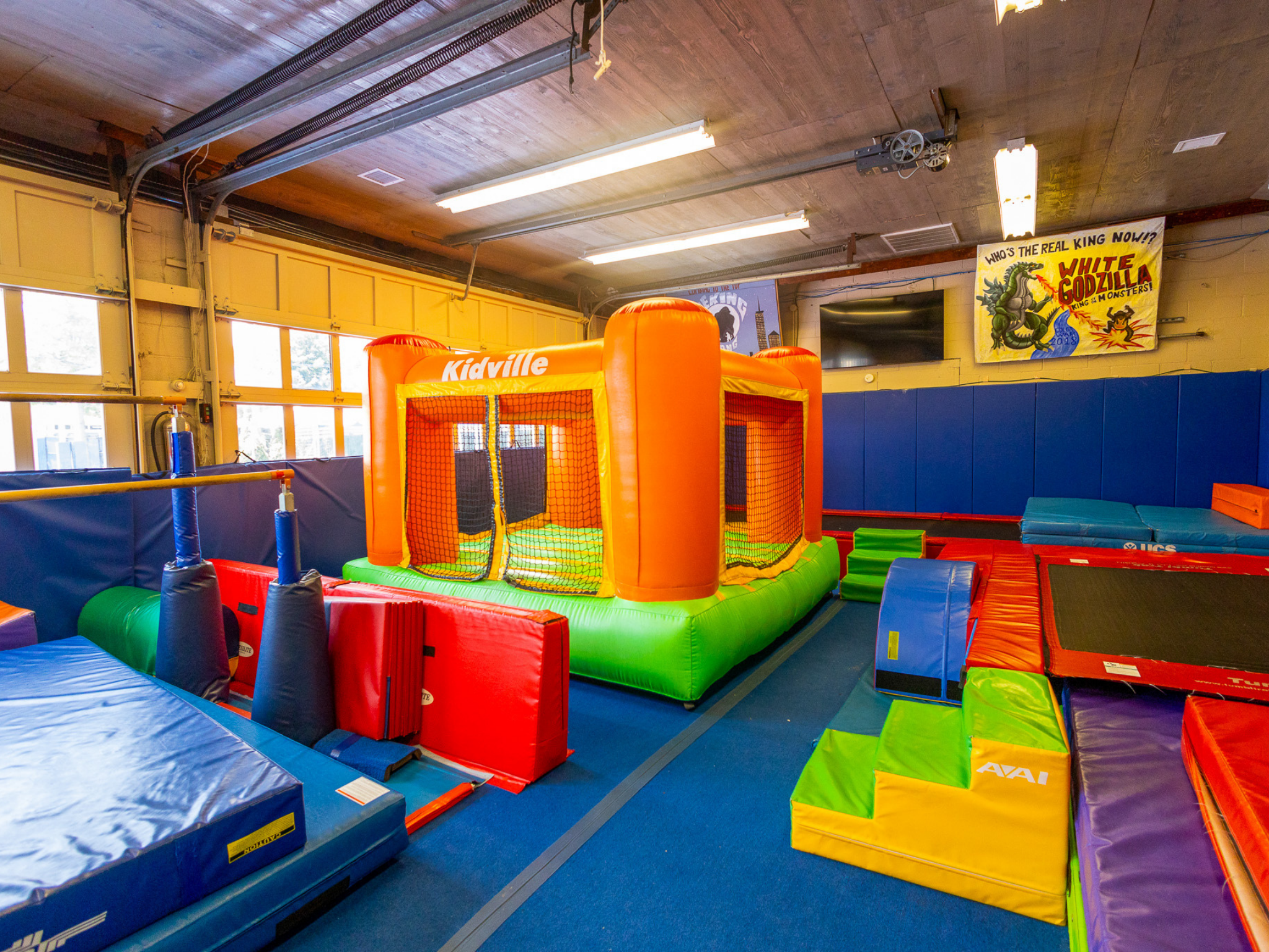indoor tumbling center featuring trampolines, bounce house, gymnastics bars, balance beam and ninja course.