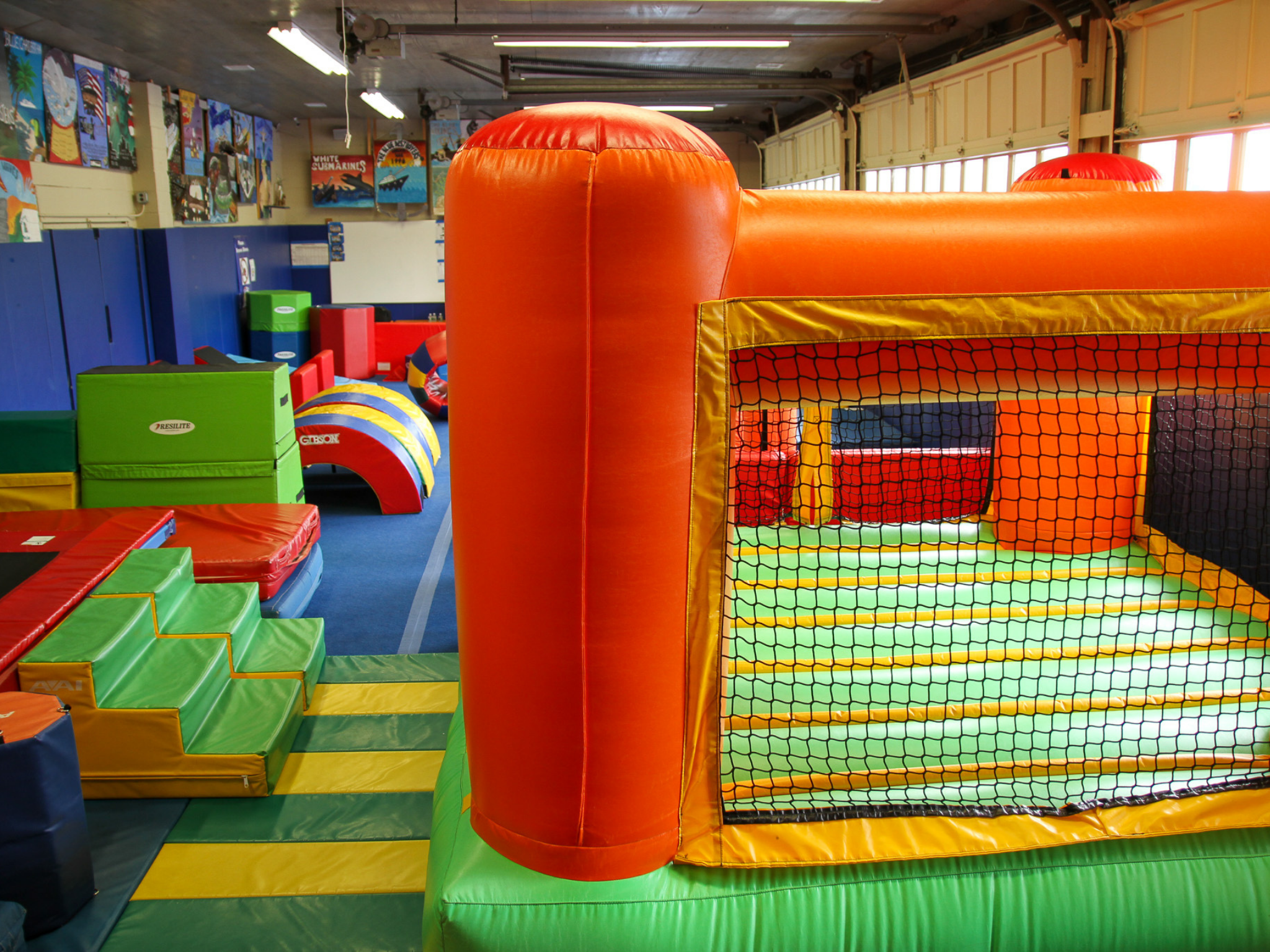 indoor tumbling center featuring trampolines, bounce house, gymnastics bars, balance beam and ninja course.
