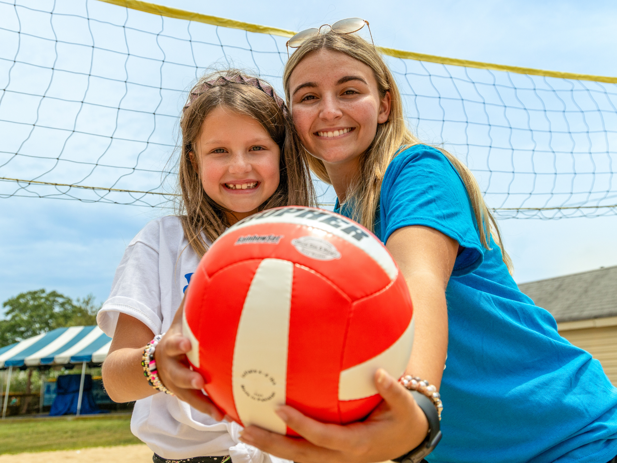 A camper and instructor ready to play beach volleyball.