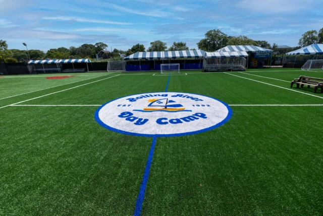 Turf field with Rolling River Day Camp logo.